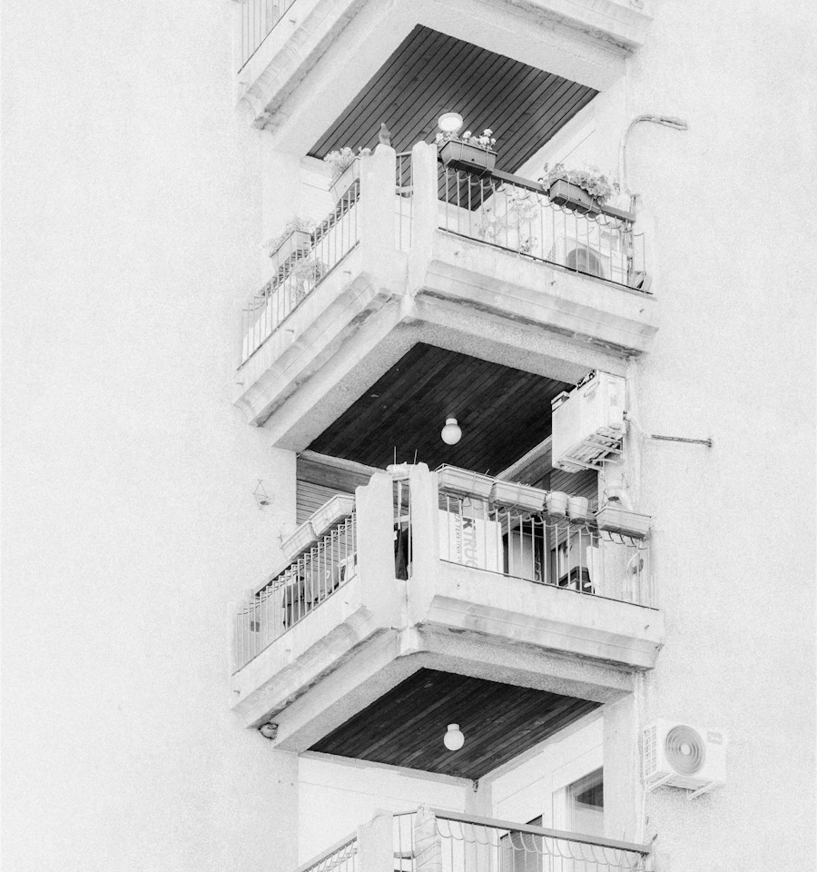 Vertical stack of concrete balconies with metal railings on a residential building facade