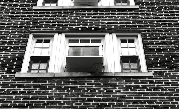 Low angle view of a brick apartment building with white window frames