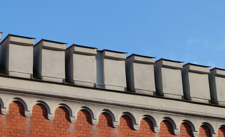 Brick building with a decorative roofline and parapet against a blue sky