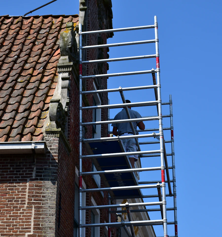 Worker on scaffolding beside an older brick building, the access used for brick pointing and repointing