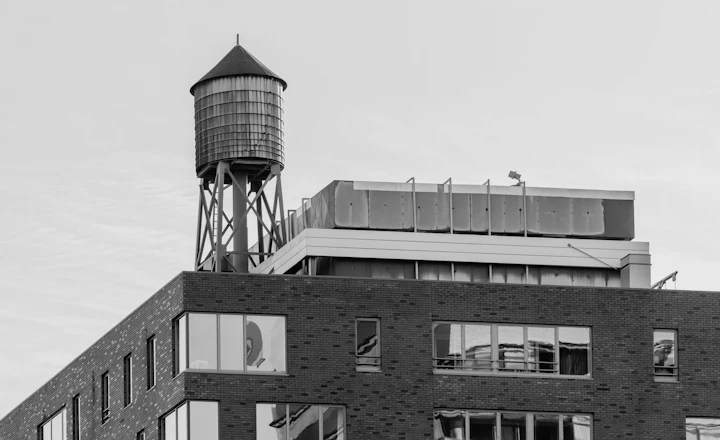 Water tower on top of a brick building roof