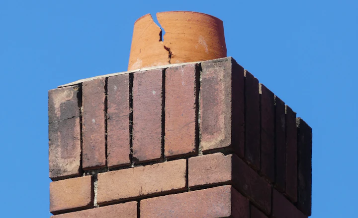 Top of a brown brick wall against a blue sky, where the joints take the most weather