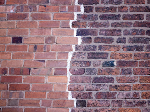 Brick wall split by a jagged line running through the mortar joints
