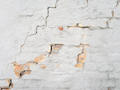 Cracks running through a white painted brick wall