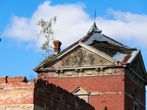 Ruined red brick building with a broken top edge and a tree growing out of it