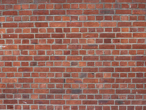 Weathered brick wall with worn, sandy mortar joints that crumble when scraped