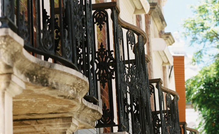Decorative iron balconies resting on brackets along an older masonry facade