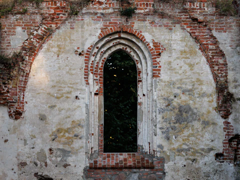 Window opening in a weathered brick and plaster wall with cracked masonry along the head above it