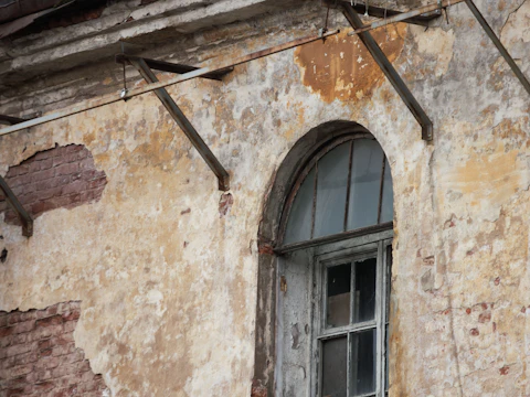 Old window in a weathered brick building, with uneven brick courses above the opening