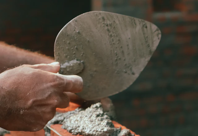 Brick wall being rebuilt course by course with a mason's trowel