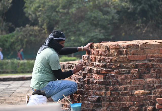 Mason repairing an old brick wall by hand outdoors