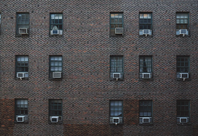 Brick apartment building facade with rows of windows and air conditioners