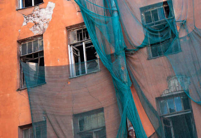 Old building facade covered with green protective netting before terra cotta repairs
