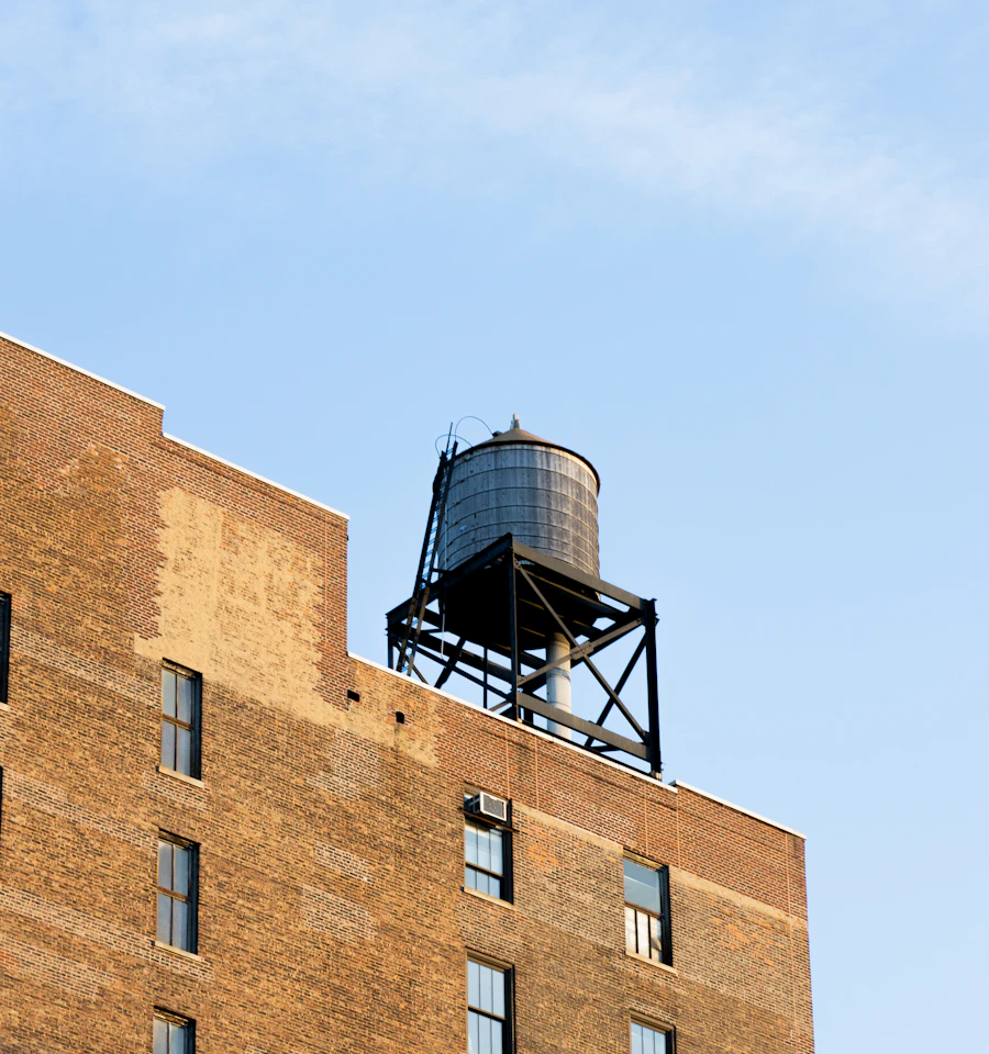 Top of a pre-war New York brick building, with its parapet and rooftop water tower against the sky