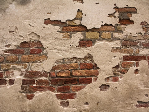 Close-up of brown brick where worn mortar joints sit back from the brick face