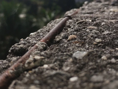 Rusted steel bar sticking out of weathered concrete