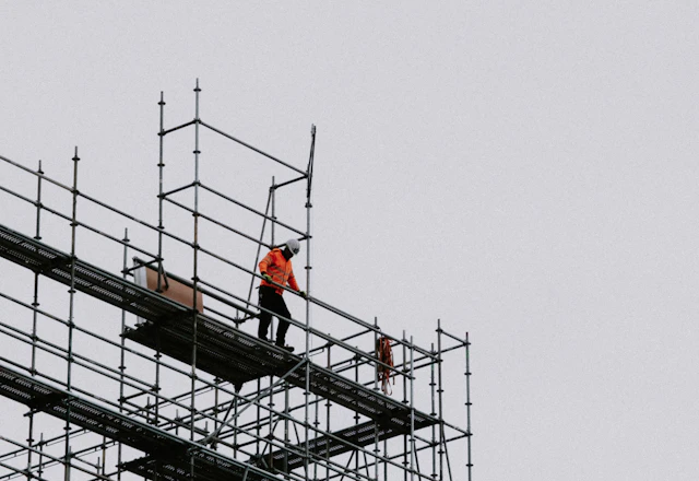 Worker standing on a scaffold on the side of a building, the access set up before lintels are opened