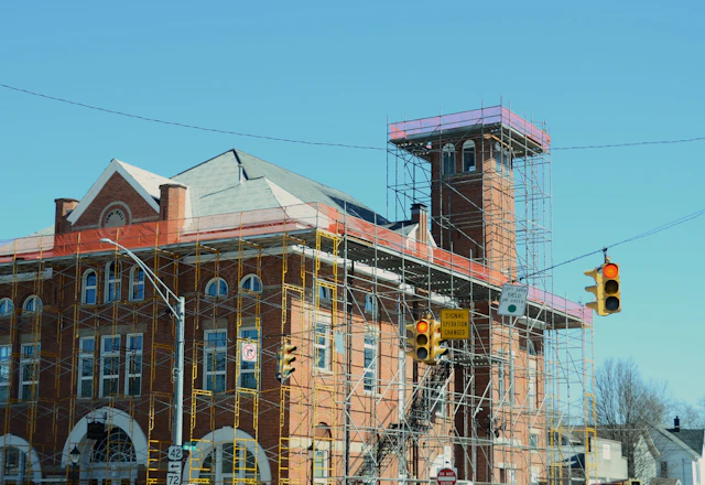 Brick building with scaffolding set up along the street for facade repointing
