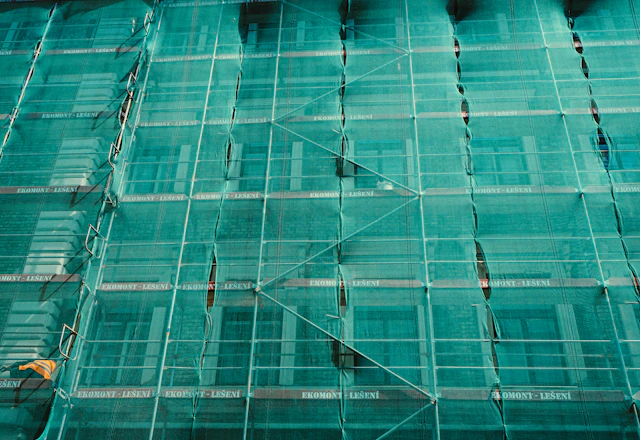 Scaffolding covered in green safety netting on a building facade