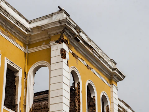 Older building with arched windows where pieces of the decorative facade have spalled away