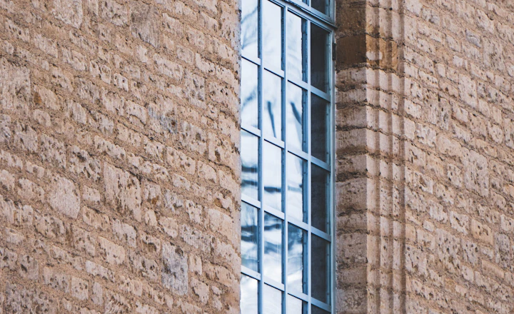 Brown brick wall around a glass window, where a steel lintel carries the brick above