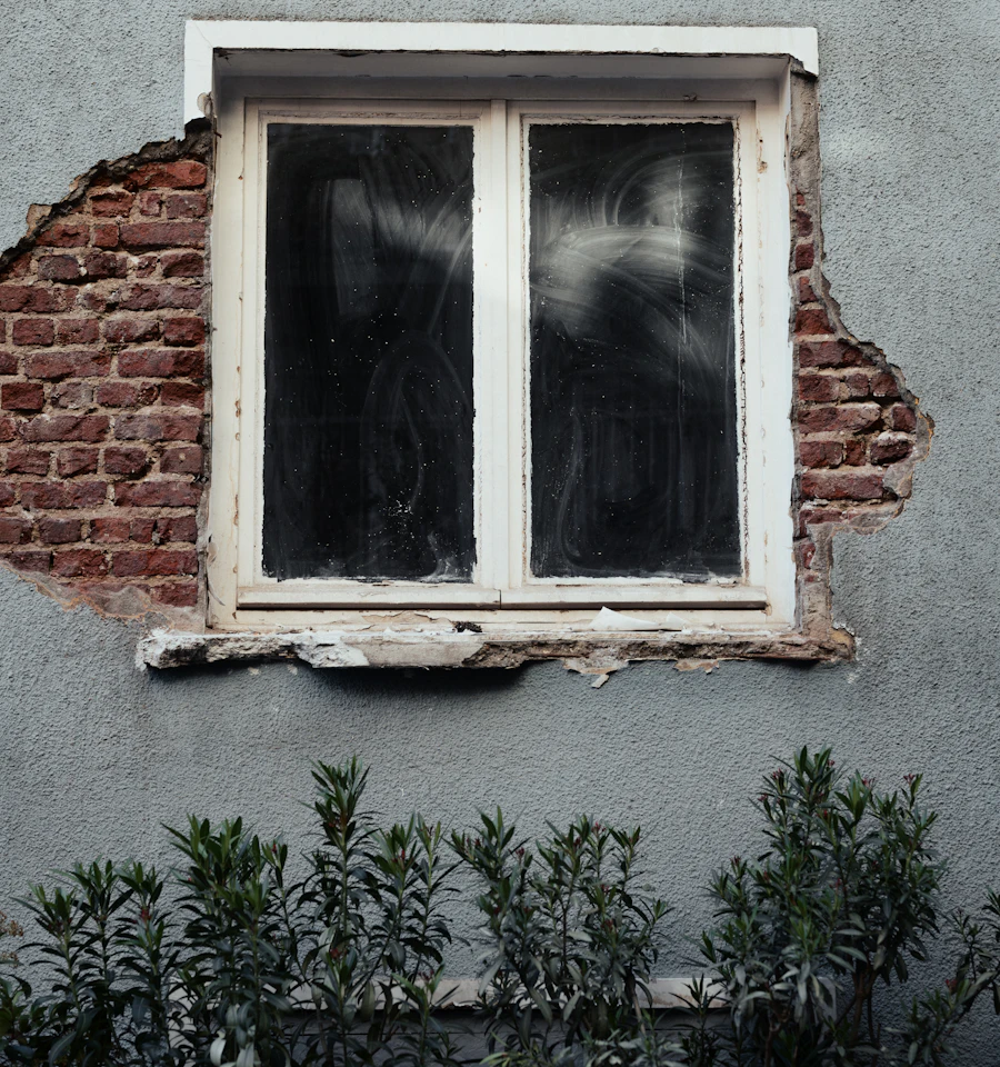 Cracked, weathered masonry around an old window opening, the kind of damage a corroding steel lintel causes above the glass