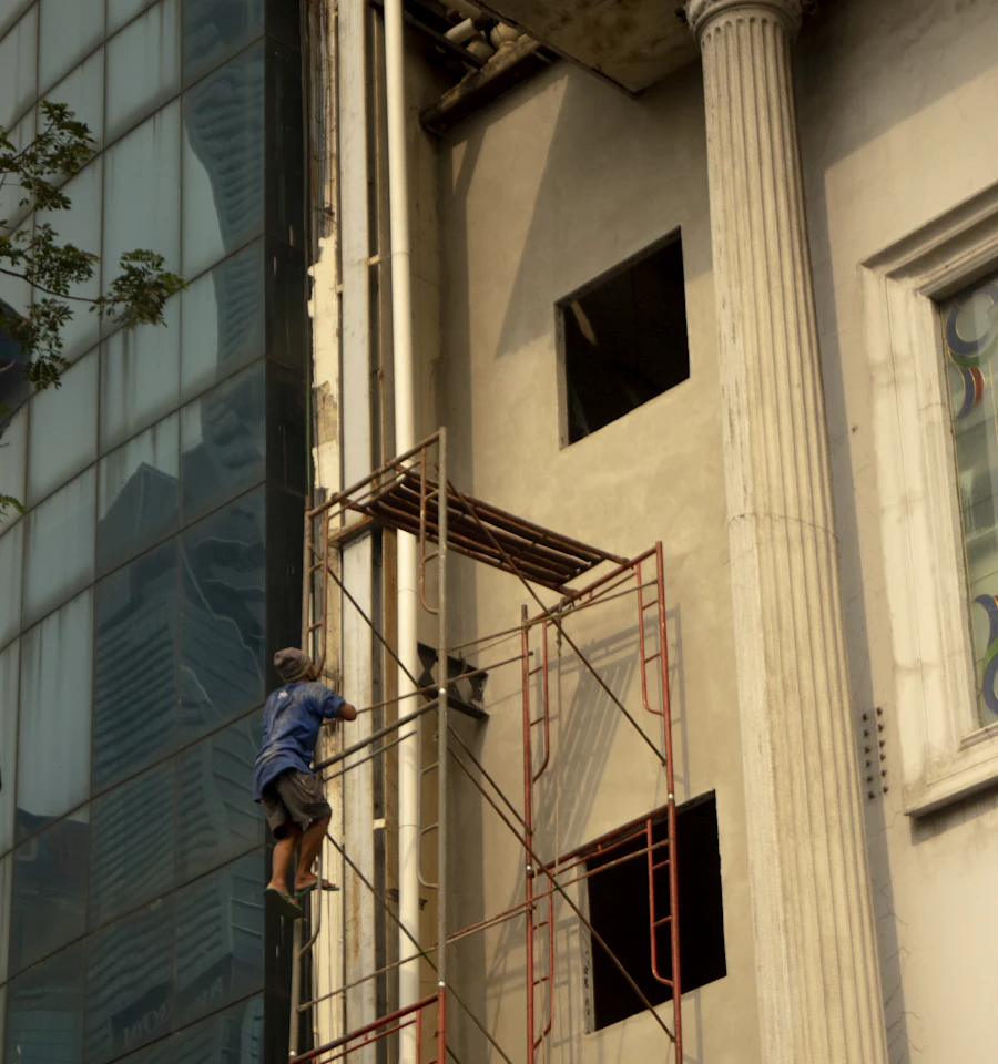 Worker standing on scaffolding beside a tall building