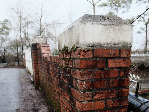 Weathered brick wall topped with a concrete coping cap