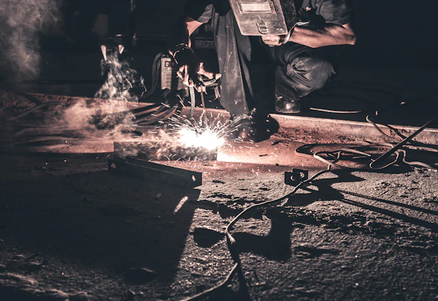 Welder joining black steel with sparks flying