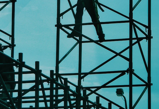 Worker standing on a black metal scaffold frame