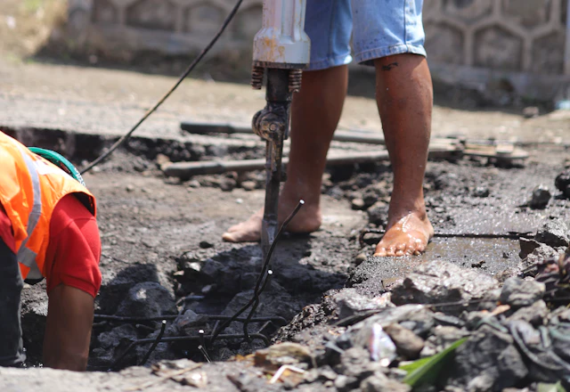 Worker in a helmet breaking out a piece of concrete